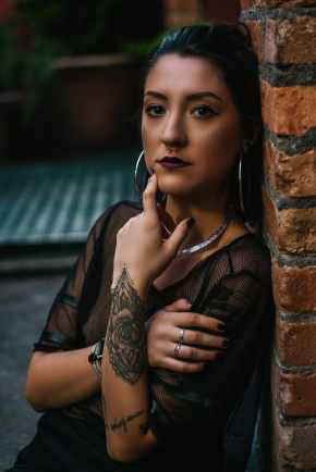 photo of tattooed woman leaning on bricked wall